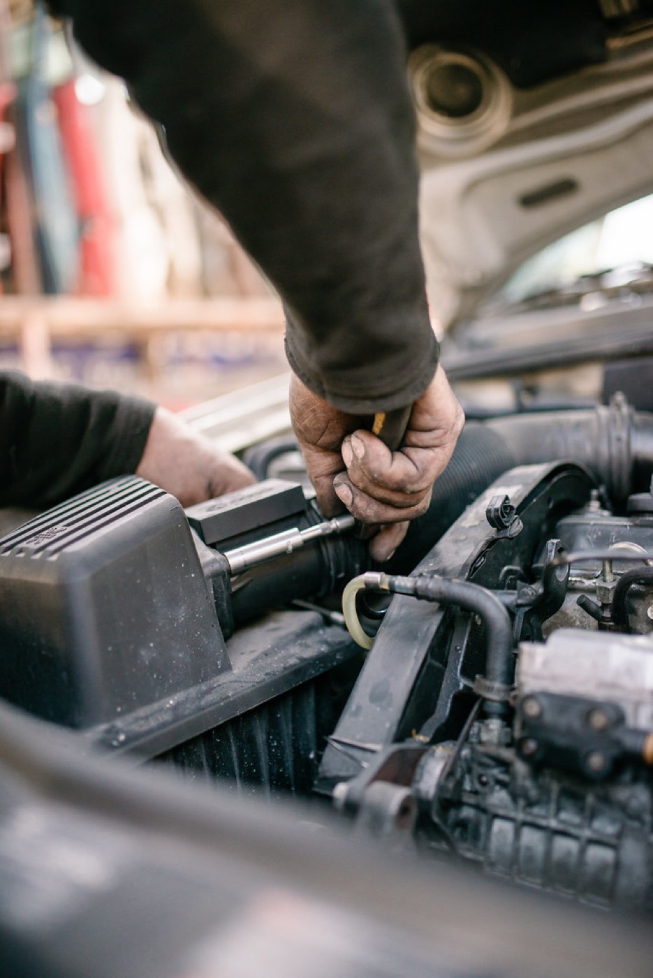 Mechanik pracujący przy silniku samochodu pod otwartą maską